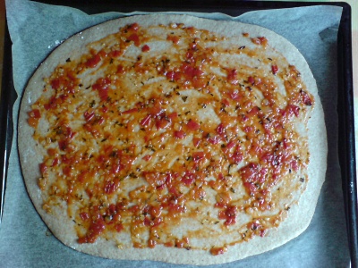 Ausgewallter Pizzateig mit Sugo bestrichen
