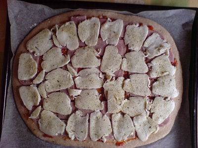 Ausgewallter Pizzateig mit Sugo bestrichen und  belegt mit Schinken und Mozarella